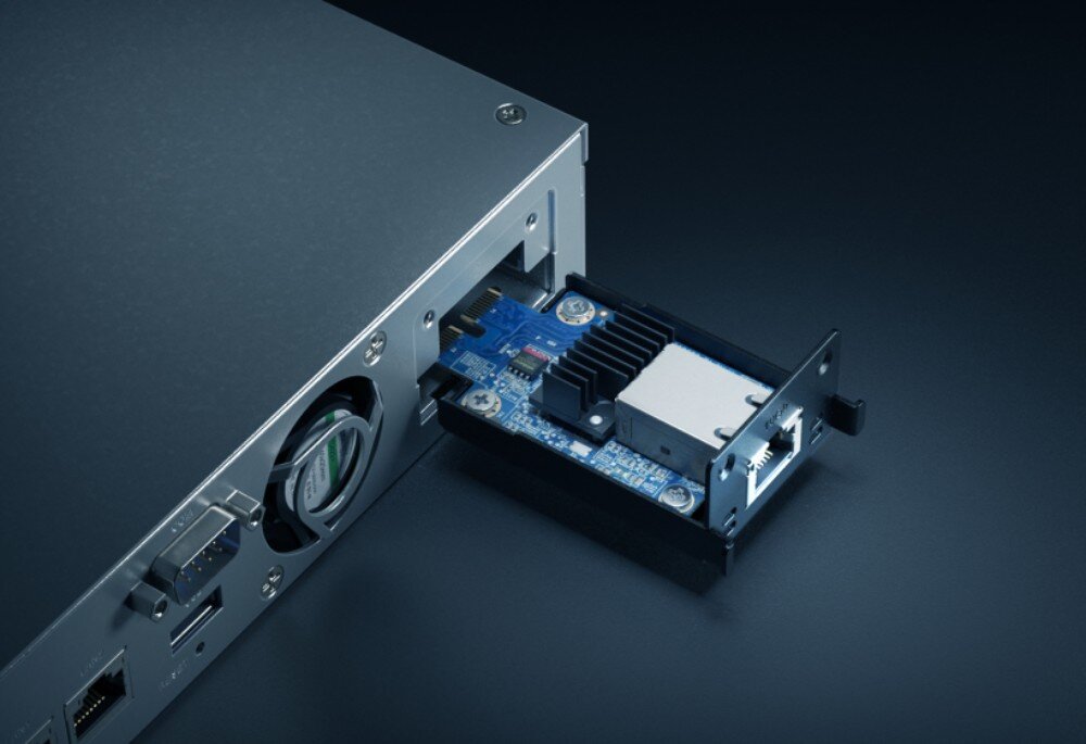 Serwer plików SYNOLOGY RS422+ Zbliżenie na tylną część obudowy serwera, do której wsuwany jest mały niebieski moduł rozszerzeń sieciowych z portem ethernetowym, porty LAN, rozbudowa