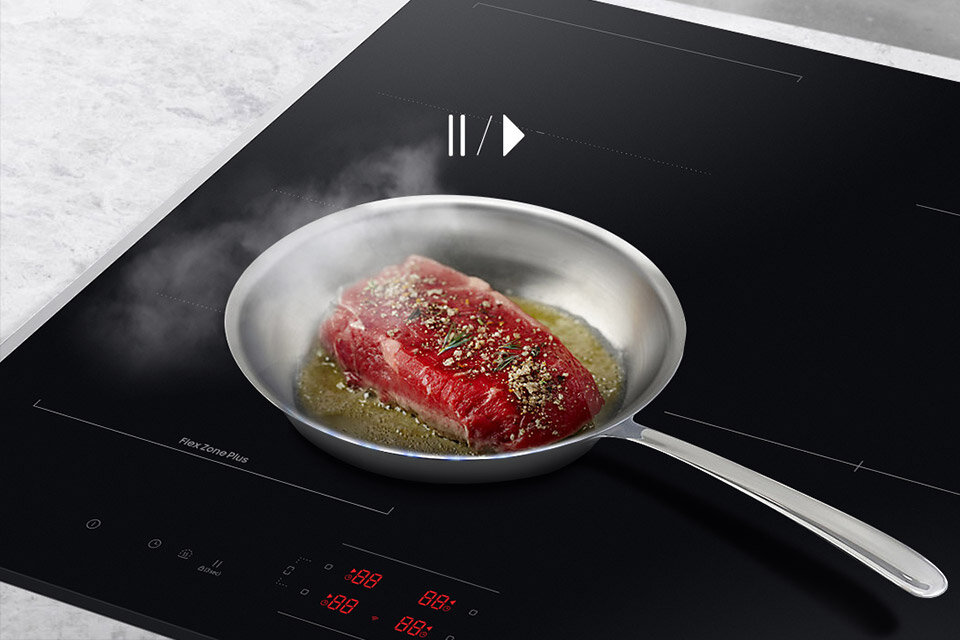 Zdjęcie patelni na włączonej płycie odnosi się do funkcji pauzy