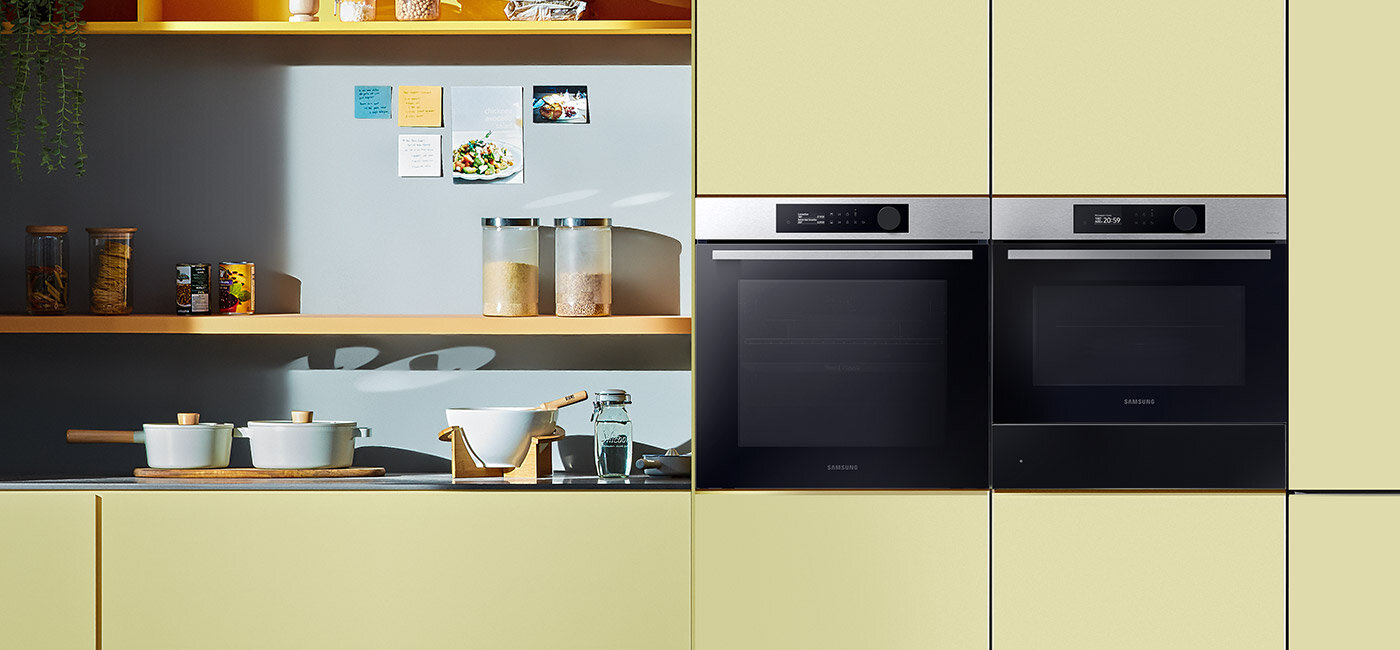 Dwa piekarniki Samsung wstawione do żółto-niebieskiego pomieszczenia kuchennego. Dwa piekarniki Samsung wstawione do żółto-niebieskiego pomieszczenia kuchennego.