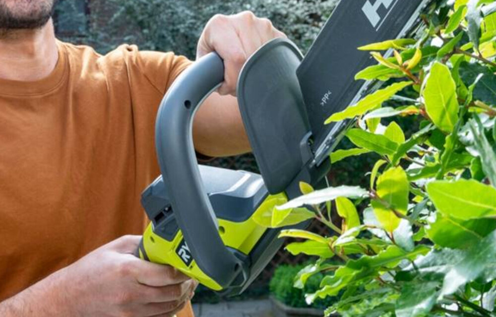 Nożyce do żywopłotu RYOBI RY18HT50A-0 500mm 18V akumulatorowe ogród zbliżenie na uchwyt w tle żywopłot uchwyt liniowy LINEA odpowiednie wyważenie lekka waga (2,4 kg) ergonomiczny kształt wspiera stabilność ruchów poprawia bezpieczeństwo równa linia cięcia