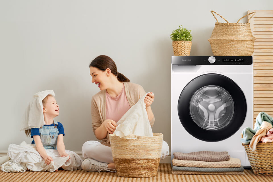 Mama z dzieckiem wyciągają pranie z bębna który może pomieścić do 8 kilogramów Mama z dzieckiem wyciągają pranie z bębna który może pomieścić do 8 kilogramów