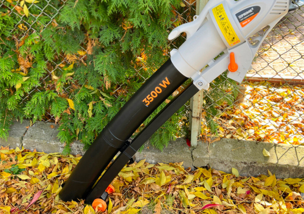 Odkurzacz do liści PRIME3 GVB41 elektryczny ogród odkurzacz ustawiony na chodniku na chodniku liście w tle płot praktyczne urządzenie 3 w 1 funkcje odkurzacza dmuchawy i rozdrabniacza zasilanie sieciowe działa nieprzerwanie