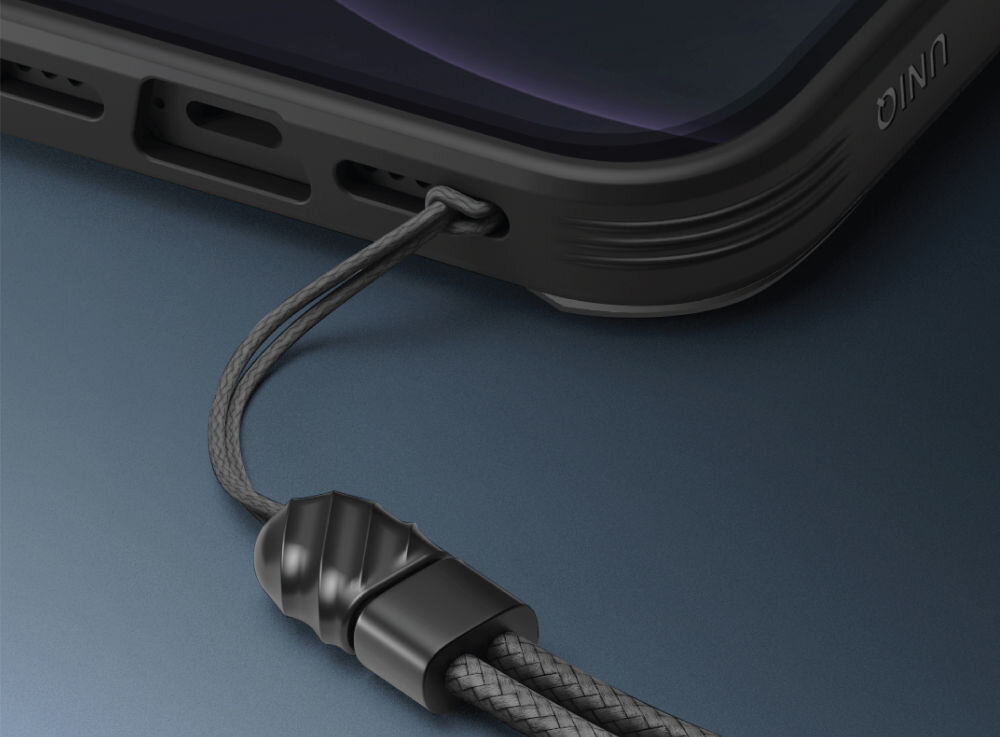 Zbliżenie na dolną część etui na telefon z widocznym napisem \'UNIQ\' oraz przymocowanym sznurkiem z plastikowym zakończeniem. Etui jest w ciemnym kolorze, a sznurek ma plecioną strukturę.