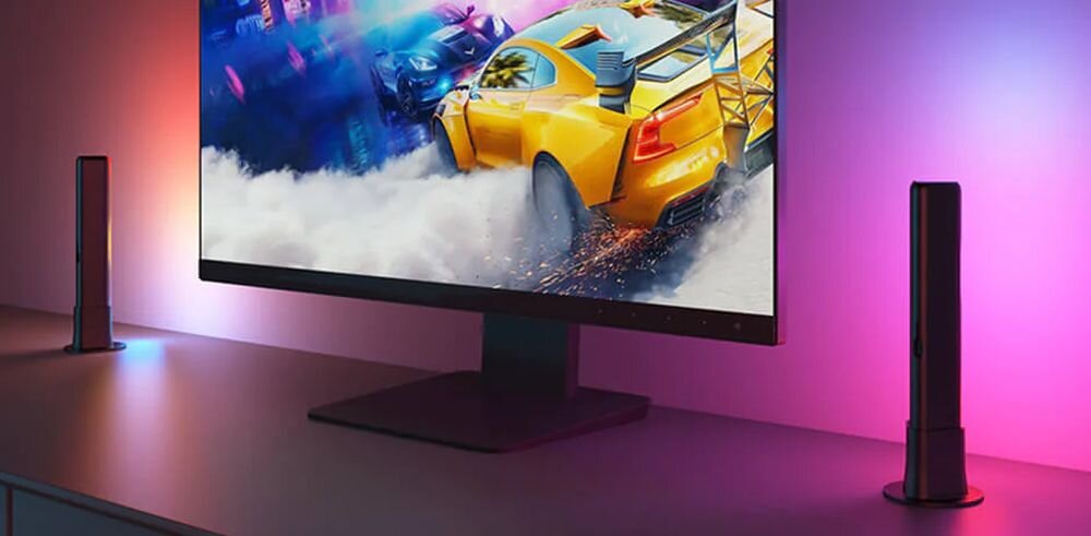 Lampa GOVEE H6056 Flow Plus RGBICWW Wi-Fi, montaż, przestrzeń, elastyczność, aranżacja, Gamingowa scena z monitorem pokazującym dynamiczną grę wyścigową, otoczonym kolorowymi podświetleniami LED Govee Glide po bokach i na biurku, w odcieniach fioletu i czerwieni.