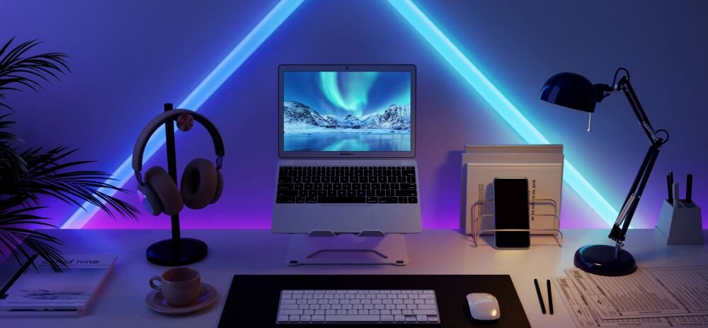 Lampa GOVEE H6062 Glide Wi-Fi/Bluetooth (7 szt.), RGBIC, kolory, segmenty, efekty, Gamingowy setup z dwoma monitorami pokazującymi abstrakcyjne grafiki, otoczony neonową taśmą Govee w kształcie fali w odcieniach zieleni i fioletu, z głośnikami i klawiaturą.