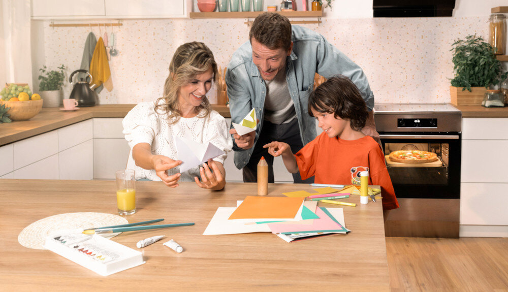 KUCHNIA GORENJE MEKIS5101I lifestyle kuchnia rodzina dziecko akcesoria plastyczne na stole kuchenka w tle kolor czarno srebrny okap półki czajnik akcesoria kuchenne na blacie