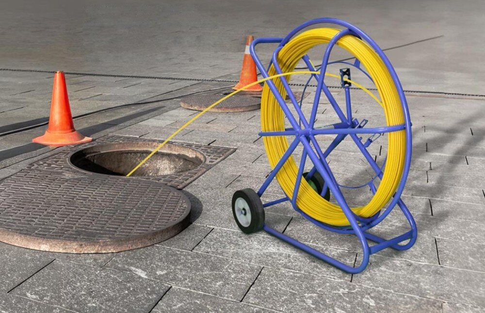 Pilot do przeciągania kabli EXTRALINK 15999 Niebieski stojak z żółtym przewodem ustawiony w pomieszczeniu gospodarczym, z naniesionymi wymiarami 63 cm wysokości, 53 cm szerokości i 20 cm głębokości