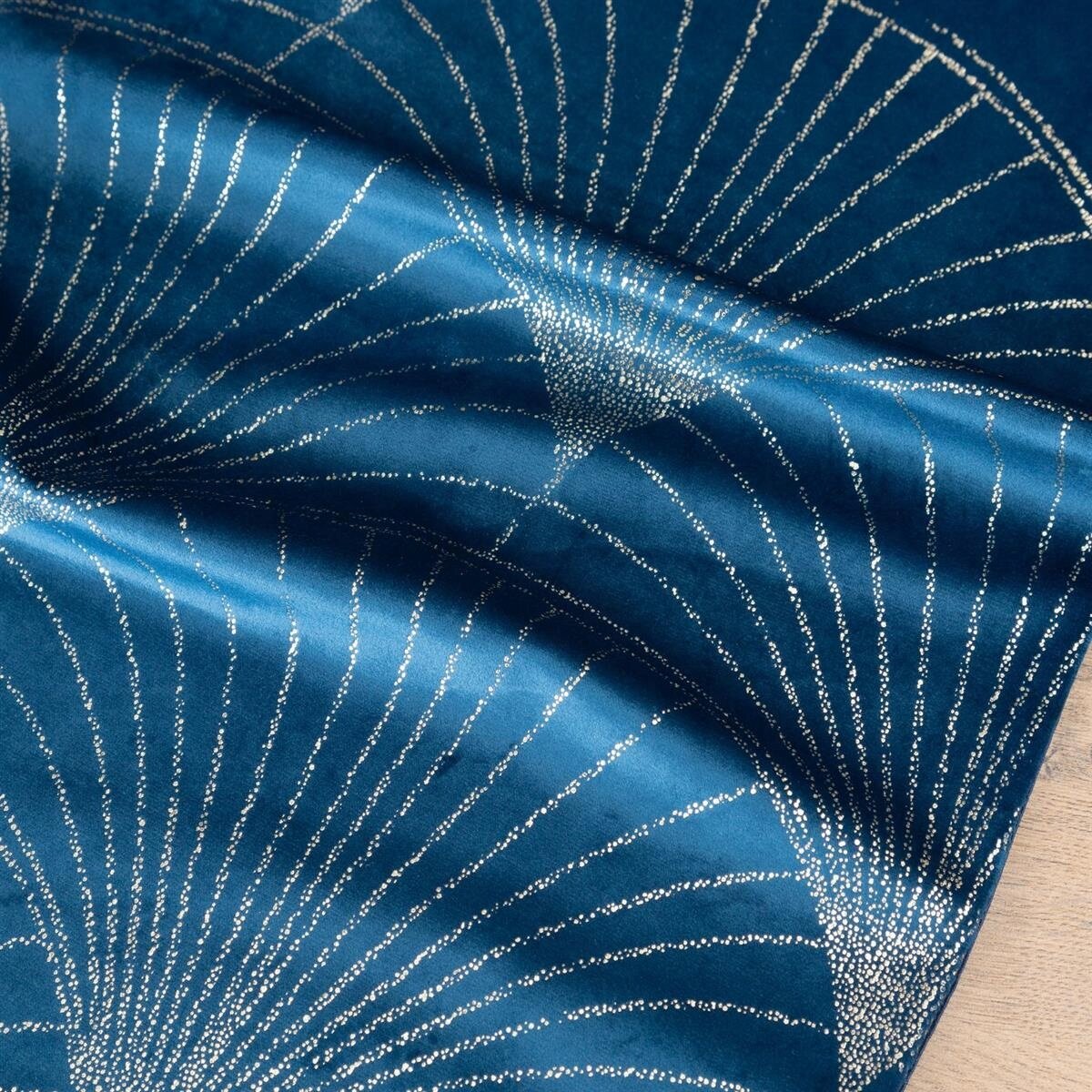 Na obrazie widoczny jest welwetowy materiał w kolorze niebieskim z dekoracyjnym wzorem w postaci srebrzystych linii rozchodzących się promieniście. Materiał ma połyskującą powierzchnię i jest lekko pofałdowany.