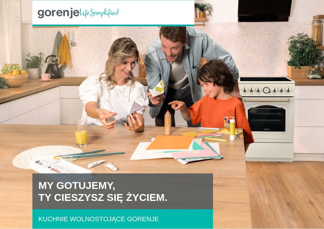 KUCHNIA GORENJE GECS5B70CLI Rodzina złożona z dwóch dorosłych i dziecka spędza czas przy kuchennym stole, wycinając kolorowe elementy z papieru, w tle widoczna jest zabudowa kuchenna z kuchnią wolnostojącą Gorenje, a u dołu znajduje się napis „MY GOTUJEMY, TY CIESZYSZ SIĘ ŻYCIEM. KUCHNIE WOLNOSTOJĄCE GORENJE”