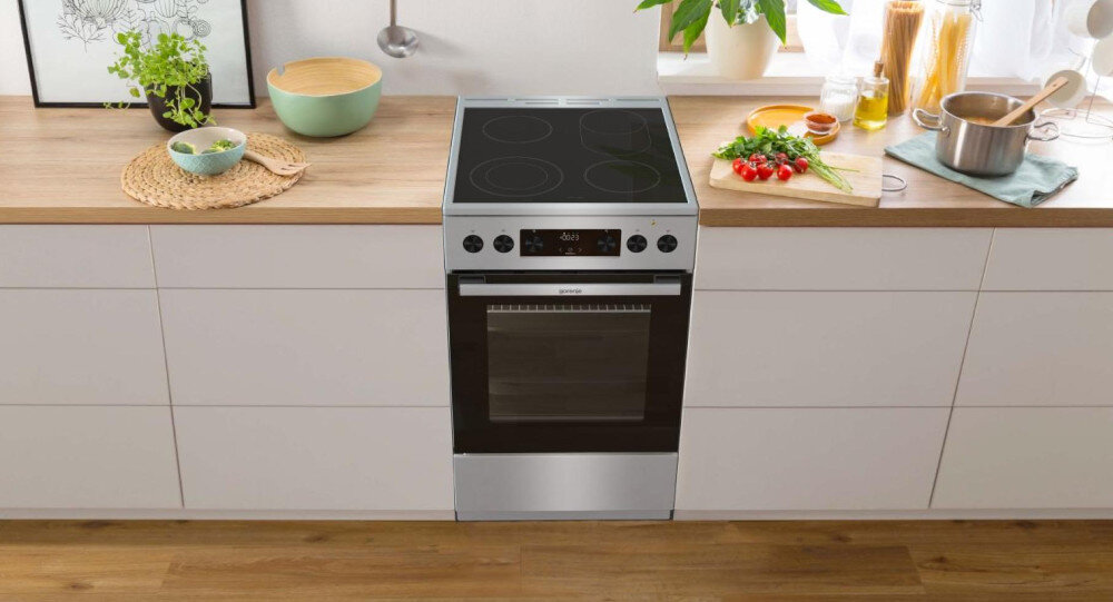 KUCHNIA GORENJE GECS5C70XPA lifestyle kuchnia rodzina dziecko akcesoria plastyczne na stole kuchenka w tle kolor czarno srebrny okap półki czajnik akcesoria kuchenne na blacie