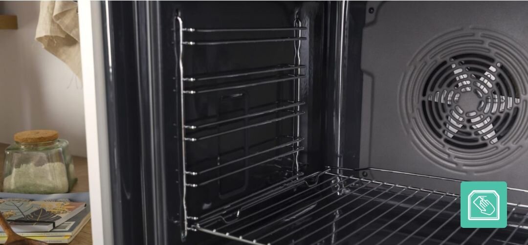 KUCHNIA GORENJE GECS5C70XPA Wnętrze piekarnika z wyraźnie widocznym wentylatorem na tylnej ścianie oraz bocznymi drabinkami do wsuwania blach, a w prawym dolnym rogu umieszczona jest ikona podkreślająca możliwość łatwego wyjmowania i czyszczenia prowadnic czyszczenie katalityczne kataliza