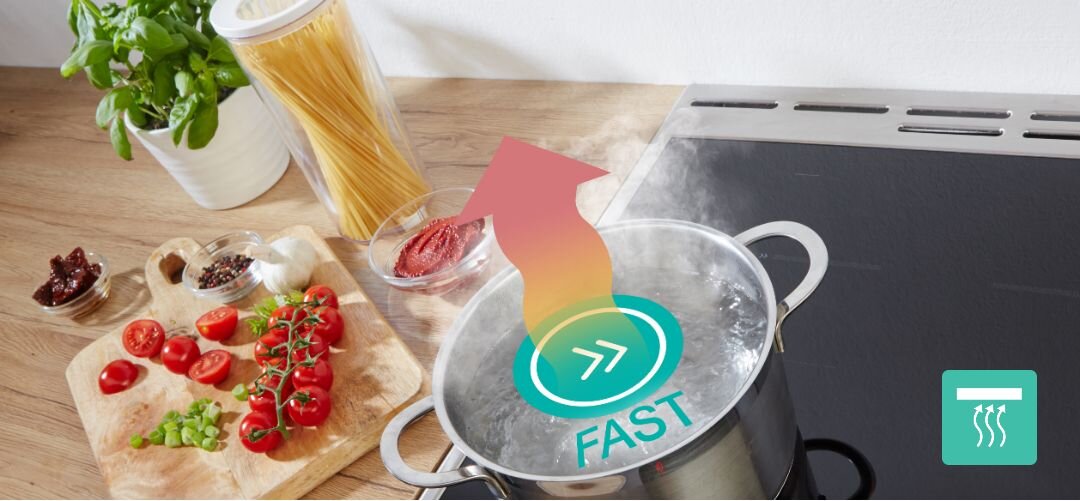 KUCHNIA GORENJE GEIT5C61XPG Widok z góry na płytę grzejną z garnkiem wrzącej wody ustawionym na polu indukcyjnym, nad którym umieszczono grafikę z napisem „FAST” i strzałką symbolizującą szybkie gotowanie, a obok na blacie leżą składniki na makaron: pomidory, przyprawy, makaron w pojemniku i doniczka z bazylią tryb przyspieszony szybkie gotowanie