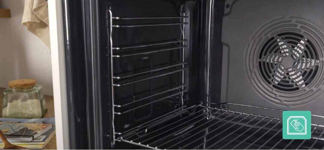 KUCHNIA GORENJE GEIT5C61XPG Wnętrze piekarnika z wyraźnie widocznym wentylatorem na tylnej ścianie oraz bocznymi drabinkami do wsuwania blach, a w prawym dolnym rogu umieszczona jest ikona podkreślająca możliwość łatwego wyjmowania i czyszczenia prowadnic czyszczenie katalityczne kataliza