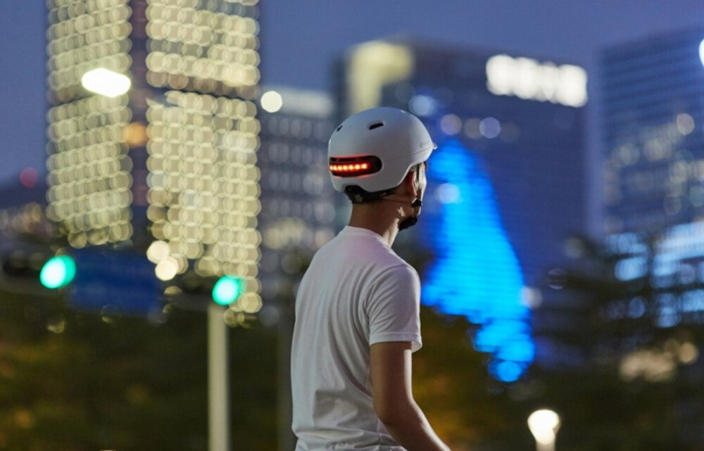 Kask LIVALL C20 Biały (rozmiar L) miasto osoba w kasku widoczna od tyłu patrzy na miasto inteligentna ochrona głowy bezpieczeństwo widoczność