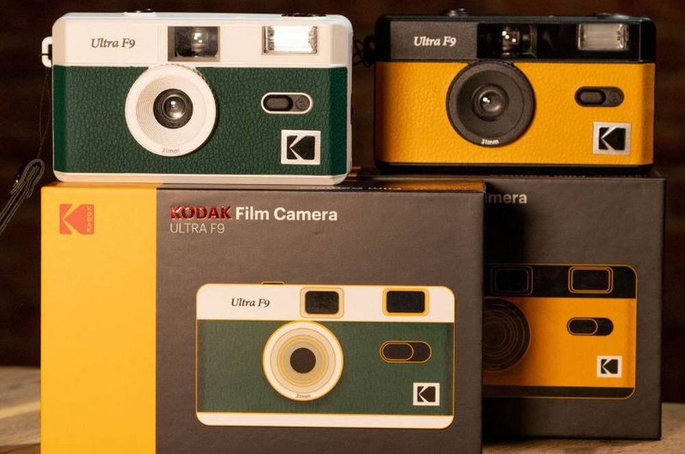 Na obrazie widoczne są trzy aparaty analogowe KODAK Ultra F9 w różnych kolorach oraz ich opakowania. Na opakowaniach znajduje się napis \'KODAK Film Camera ULTRA F9\'.