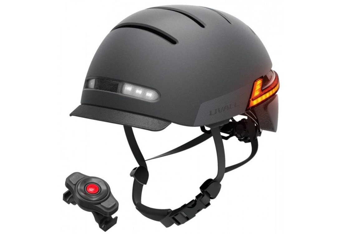 Czarny kask z wbudowanymi lampkami LED i regulowanym paskiem pod brodą. Obok kasku znajduje się małe urządzenie z czerwonym przyciskiem.
