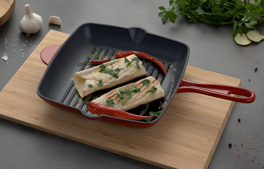 Patelnia MG HOME Infinito 26 cm patelnia położona na desce ciemny blat patelnia z posiłkiem ciemna w środku czerwona na zewnątrz do każdej kuchni