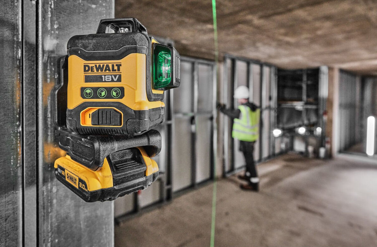 Laser krzyżowy DEWALT DCLE34031D1-QW, Precyzja, Dokładność, tolerancja, wyrównania, laser zamontowany do ściany przy pomocy uchwytu, w tle mężczyzna w trakcie remontu