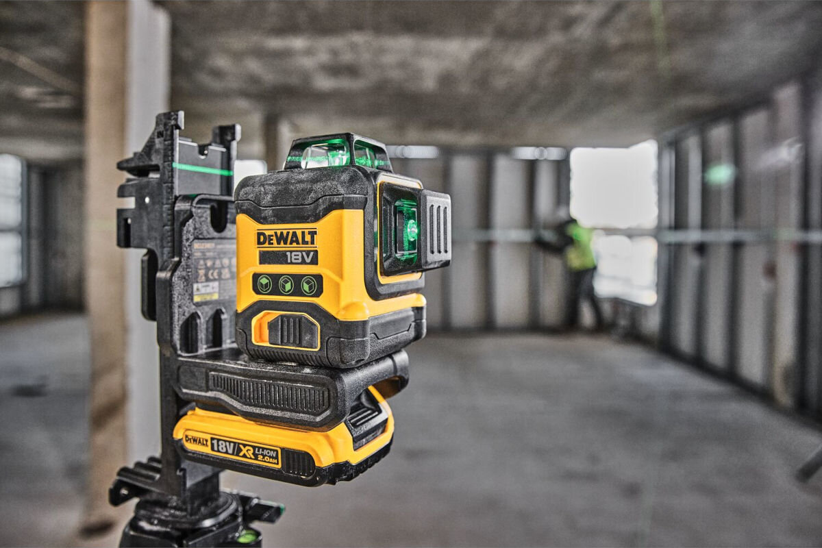 Laser krzyżowy DEWALT DCLE34031D1-QW, akumulatory, seria, warsztat, czas, 11 godzin, laser zamocowany do uchwytu na słupie, w tle robotnik na budowie