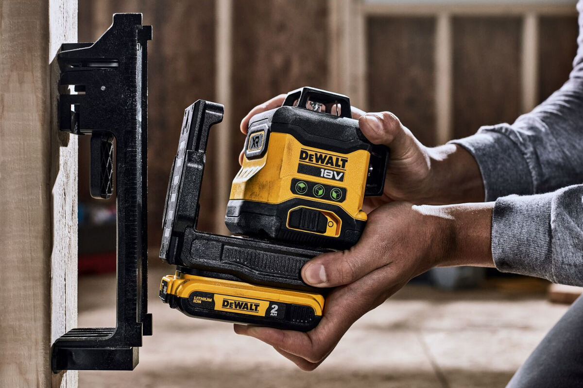 Laser krzyżowy DEWALT DCLE34031D1-QW, statywy, ścienne, montaż, uchwyt, dłonie kierują laser do mocowania ściennego lasera