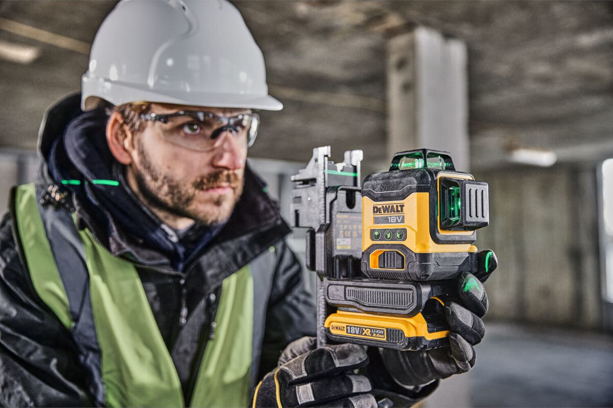 Laser krzyżowy DEWALT DCLE34031D1-QW, pulsacyjny, impulsowy, detektor, tryb, 100m, mężczyzna obsługuje laser zamontowany na statywie