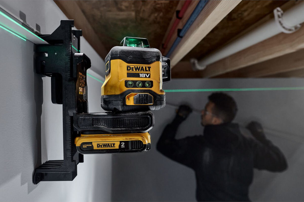 Laser krzyżowy DEWALT DCLE34031D1-QW, testy, upadki, wytrzymałość, konstrukcja, laser zamontowany do ściany remontowanego budynku, w tle mężczyzna podczas remontu