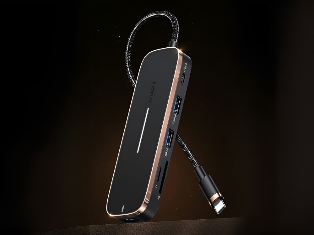 Hub USAMS SJ575HUB01 Hub USB-C z podświetleniem i owalnym kształtem unosi się na ciemnym tle. Widoczne są porty USB, czytniki kart oraz przewód zakończony wtyczką, 
            hub adapter technologia gadżet laptop komputer