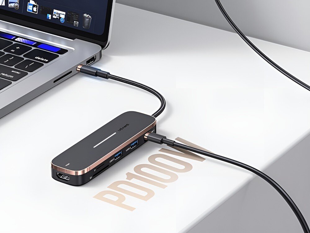 Hub USAMS SJ575HUB01 Hub USB-C podłączony do laptopa leży na białym blacie. Do urządzenia wpięty jest przewód i widoczne są porty oraz oznaczenie PD100W, 
            hub usba usc power delivery 100w hdmi sd microsd