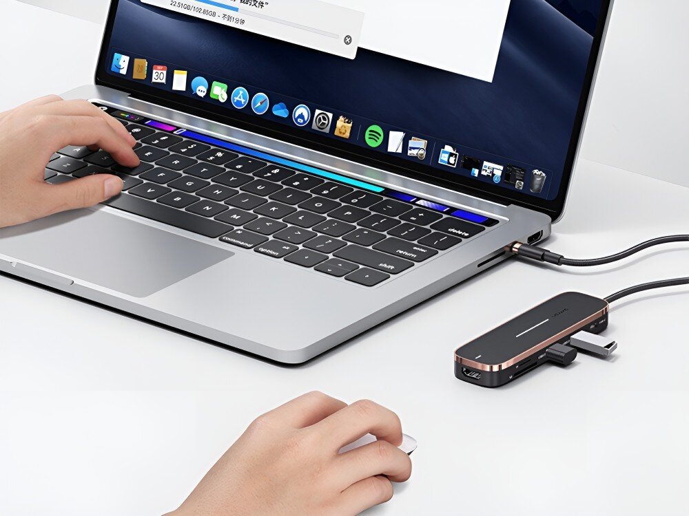 Hub USAMS SJ575HUB01 Osoba korzysta z laptopa i myszki. Obok komputera leży podłączony hub USB-C z wpiętymi urządzeniami, 
            usba usb hdmi 4k pd sd microsd