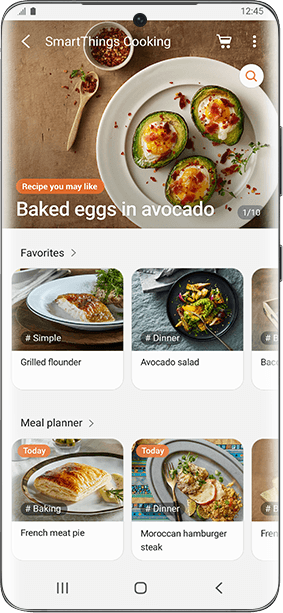 Ekran aplikacji SmartThings Cooking z przepisem na \'Baked eggs in avocado\'. Widoczne są również sekcje \'Favorites\' z daniami \'Grilled flounder\' i \'Avocado salad\' oraz \'Meal planner\' z \'French meat pie\' i \'Moroccan hamburger steak\'.
