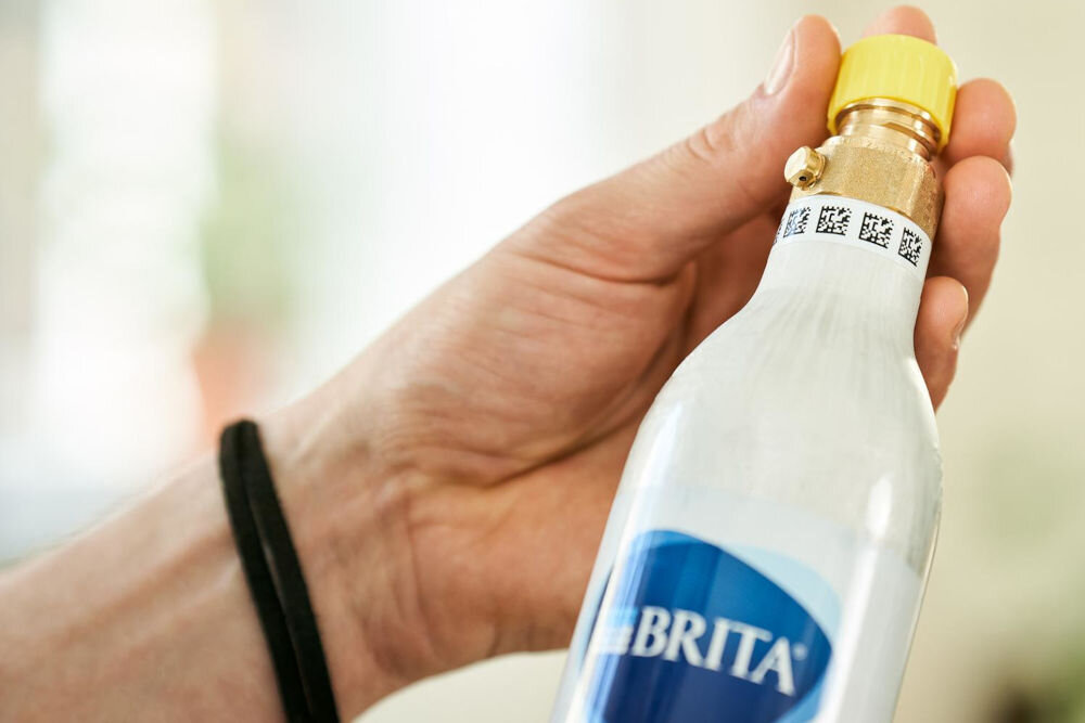 Nabój BRITA Sodaone CO2 1043744 zbliżenie dłoni trzymającej nabój z dwutlenkiem węgla do saturatorów wody Brita