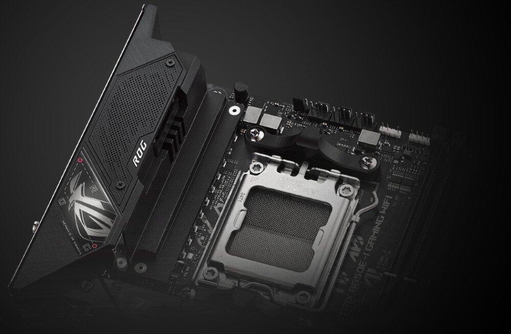 Płyta główna ASUS ROG Strix B650E-I Gaming WiFi Fragment płyty głównej z widocznym gniazdem procesora AM5 oraz czarnym radiatorem z logo 'ROG' po lewej stronie, sekcja zasilania, płyta PCB, podkręcenie
