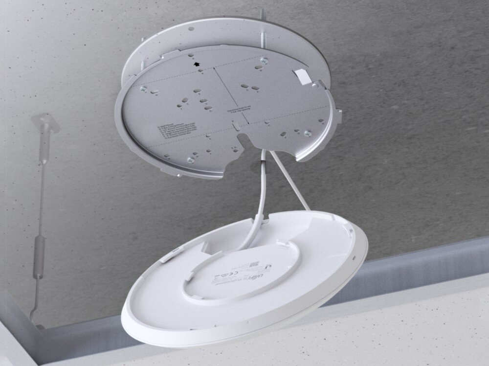 Punkt dostępu UBIQUITI U6 Enterprise Spód urządzenia sieciowego w trakcie instalacji na metalowym uchwycie montażowym przytwierdzonym do sufitu