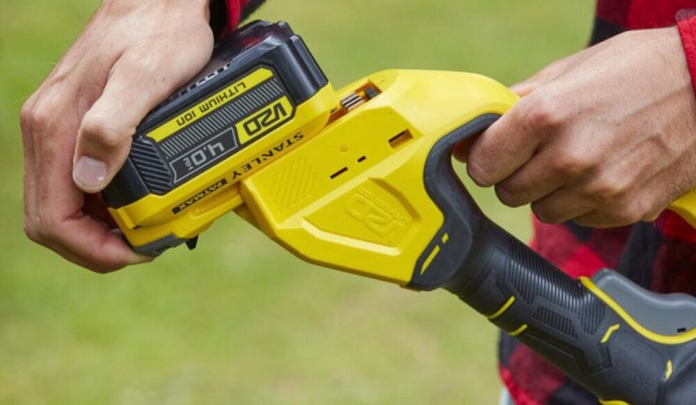 Piła akumulatorowa STANLEY Fatmax SFMCPS620M1 rozmazane zielone tło osoba wkłada akumulator do piły system akumulatorowy STANLEY FATMAX V20 18 V zasilanie wielu narzędzi jednym akumulatorem litowo-jonowym bez efektu pamięci zintegrowany wskaźnik naładowania w zestawie akumulator o pojemności 4.0Ah i ładowarka 2A