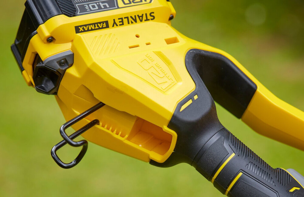 Piła akumulatorowa STANLEY Fatmax SFMCPS620M1 rozmazane zielone tło zbliżenie na hak zintegrowany hak kompatybilny z systemem STANLEY Track uporządkowane i bezpieczne przechowywanie narzędzia ogranicza ryzyko przypadkowych uszkodzeń bezpieczeństwo domowników