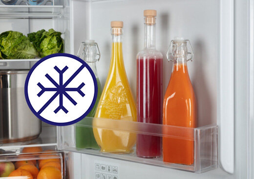 Zbliżenie na drzwi lodówki, na których są butelki z napojami. Płatek śniegu jako oznaczenie systemu Total No Frost.