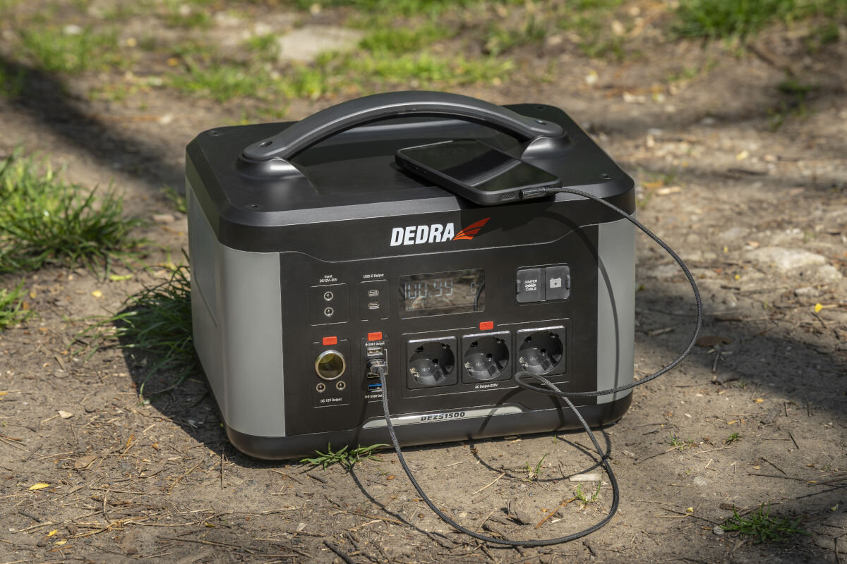 Stacja zasilania DEDRA DEZS1500 1500W Bank energii porty gniazda wejścia oświetlenie, stacja stoi na ziemi w słoneczny dzień