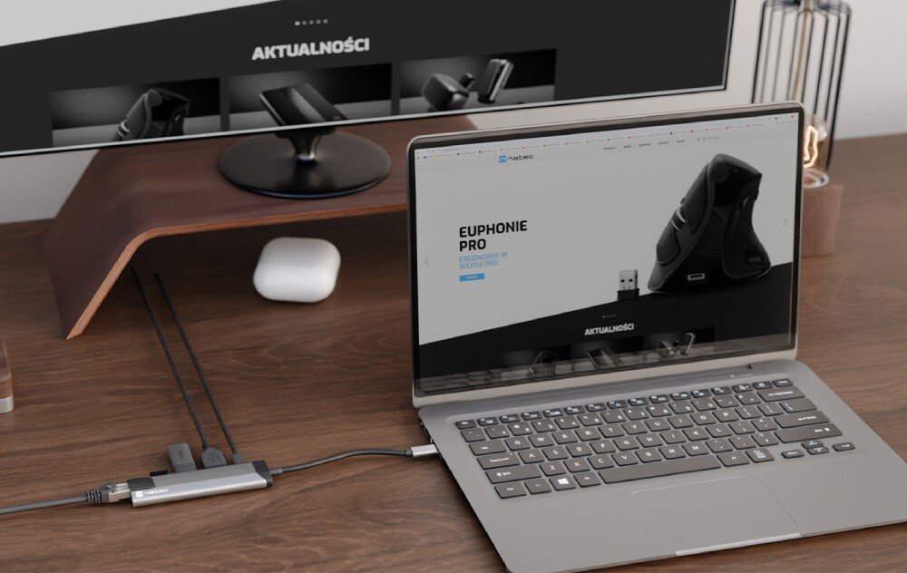 Hub NATEC Fowler Go 5w1 Laptop podłączony do monitora z stacją dokującą na drewnianym biurku.