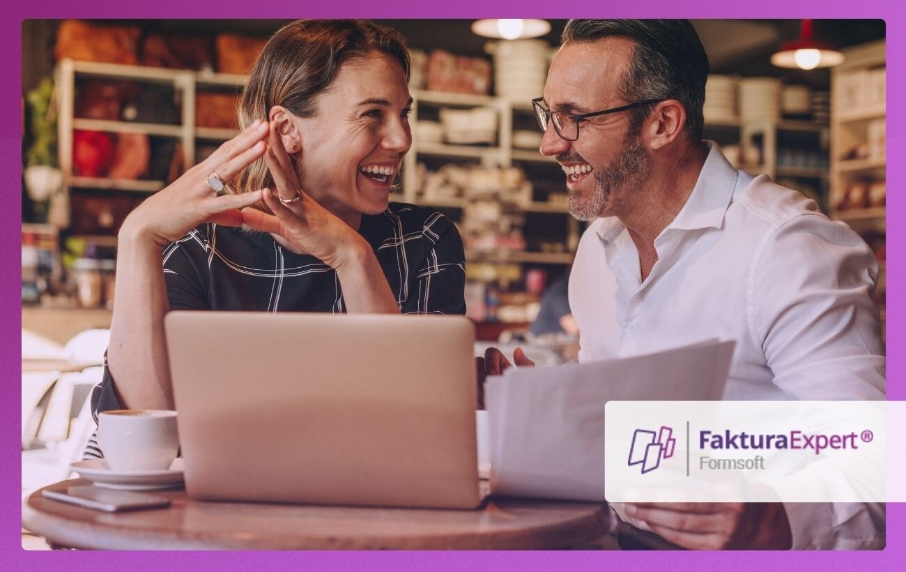kobieta i&nbsp;mężczyzna w&nbsp;średnim wieku uśmiechają się do siebie; przed nimi na stole leży otwarty laptop, mężczyzna trzyma w&nbsp;ręku kartki papieru; w&nbsp;prawym dolnym rogu logo Faktura Expert.