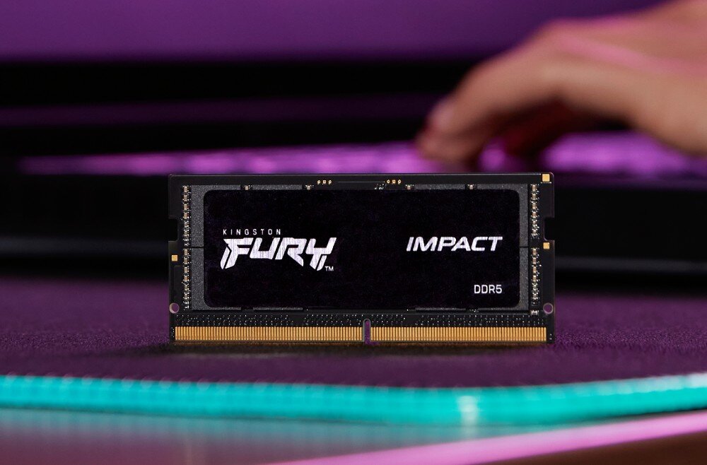 Pamięć RAM KINGSTON Fury Impact Czarny moduł pamięci RAM z białym logo 'FURY' na tle zamazanej dłoni i fioletowego oświetlenia