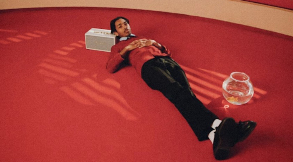 Głośnik MARSHALL STANMORE III Bluetooth 5.2 aktualizacje OTA aplikacja, głosnik stojący na ziemi, osoba opierająca głowę o głośnik