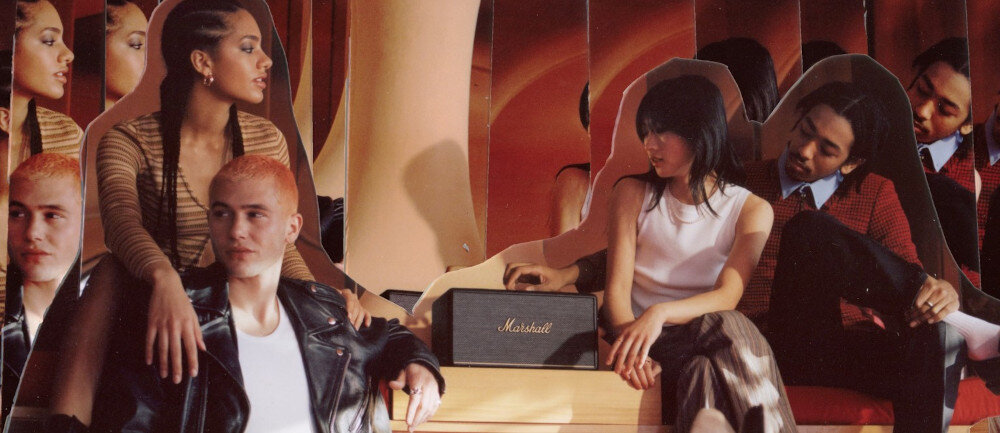 Głośnik MARSHALL STANMORE III wejście 3.5 mm RCA połączenie przewodowe, głośnik stojący na drewnianym postumencie, ludzie siedzący obok głośnika