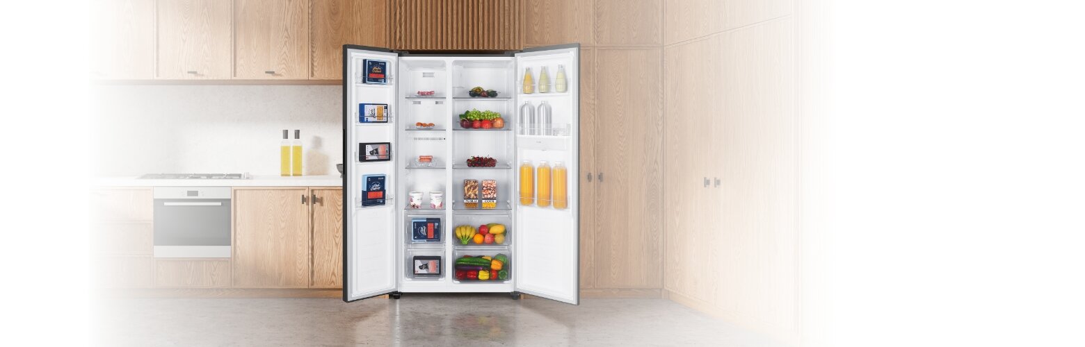 Lodówka MPM-439-SBS-15/ND z otwartymi drzwiami w drewnianej zabudowie kuchennej. Urządzenie wypełnione żywnością.