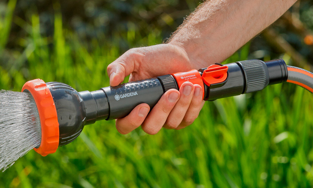 Zraszacz prosty GARDENA Profi-System trzyfunkcyjny z sitkiem 02847-20 rozmyte zielone tło osoba trzyma zraszacz w dłoni wszechstronne zastosowanie do mycia do podlewania uniwersalność