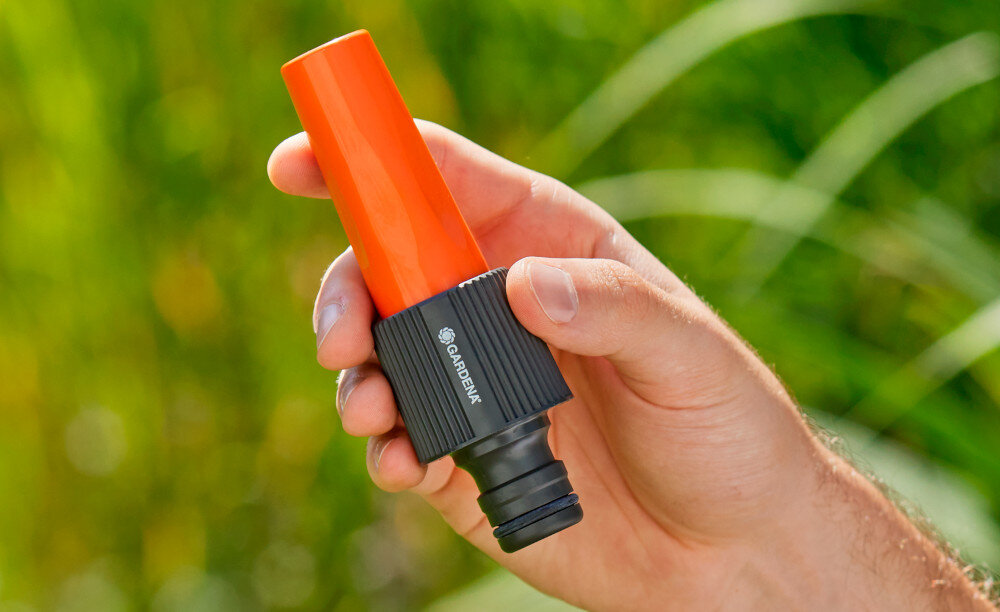 Pistolet zraszający GARDENA Profi-System 02818-20 ogród rozmyte zielone tło osoba trzyma zraszacz w dłoni wszechstronne zastosowanie do podlewania i czyszczenia powierzchni zadbany ogród i dom