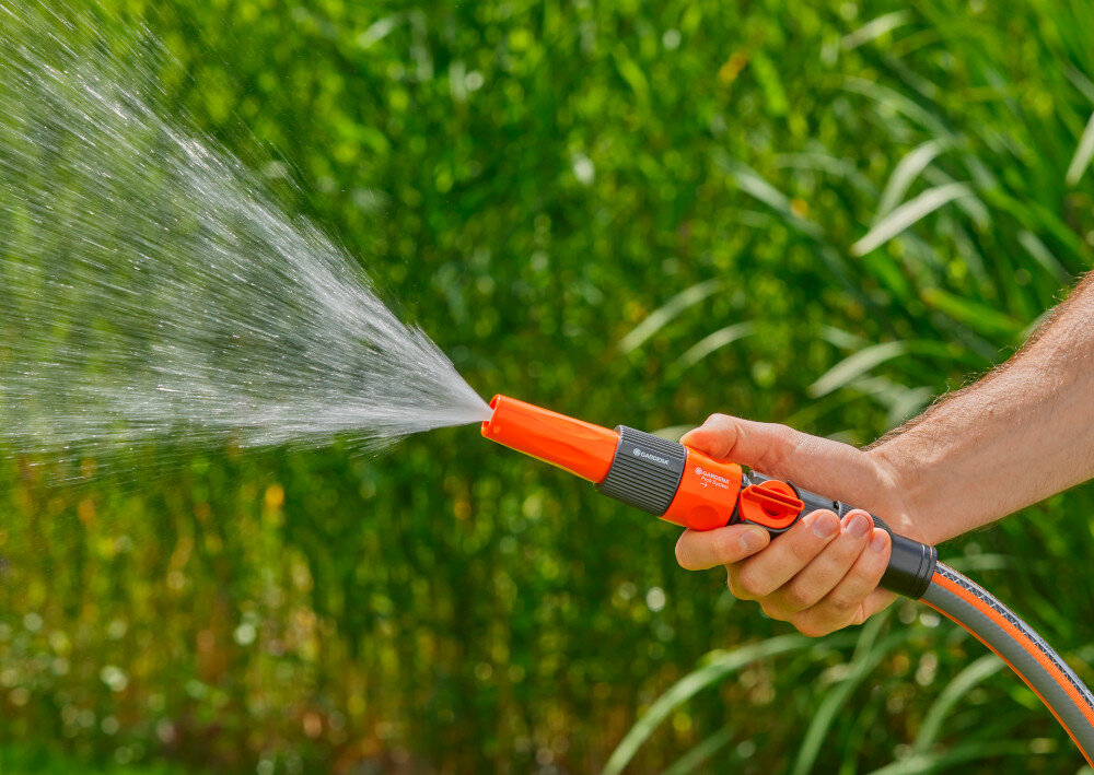 Pistolet zraszający GARDENA Profi-System 02818-20 osoba trzyma zraszacz w dłoni ze zraszacza płynie woda w tle zielone rośliny przepływ dużych ilości wody ułatwia podlewanie rozległych obszarów i sprawne mycie zabrudzonych miejsc efektywność pracy jest wyższa niż przy tradycyjnym podlewaniu Efektywność pracy jest wyższa niż przy tradycyjnym podlewaniu