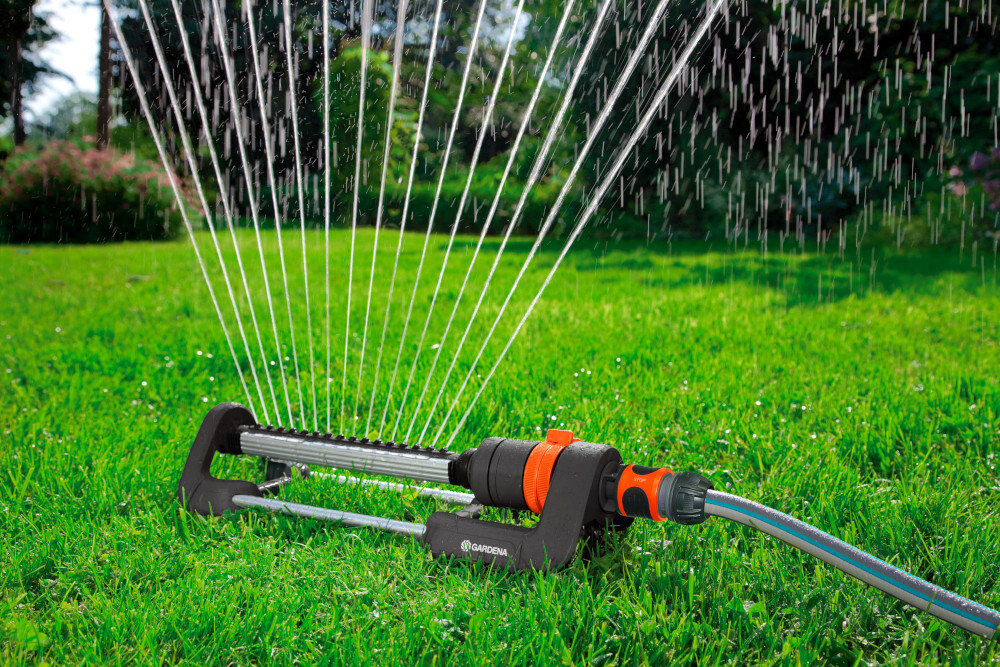 Zraszacz GARDENA Aqua S 18700-20 trawnik zraszacz na trawniku w tle drzewa krzewy kwiaty konstrukcja wzmocniona elementami metalowymi stabilność odporny na uszkodzenia mechaniczne