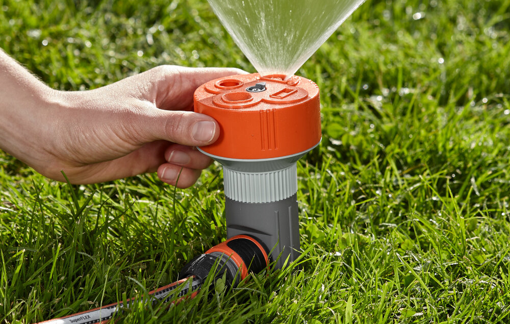 Zraszacz GARDENA Classic Twist 02068-20 trawnik osoba trzyma głowicę zraszacza w dłoni ustawia zraszacz obrotowe pokrętło dopasować kształt strumienia do wybranego obszaru