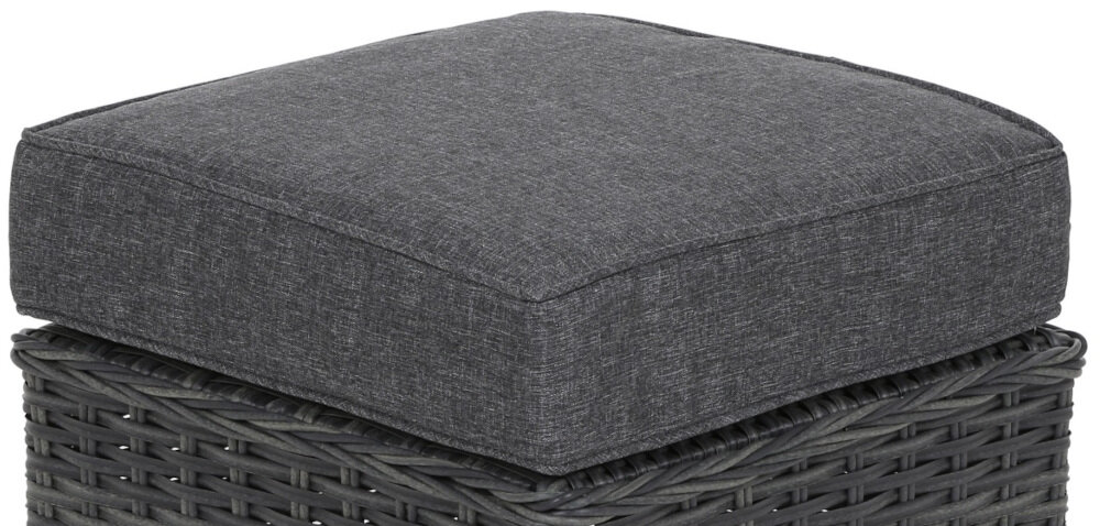 Na obrazie widoczna jest szara poduszka umieszczona na plecionym siedzisku z ciemnego materiału. Poduszka ma prostokątny kształt i gładką powierzchnię.