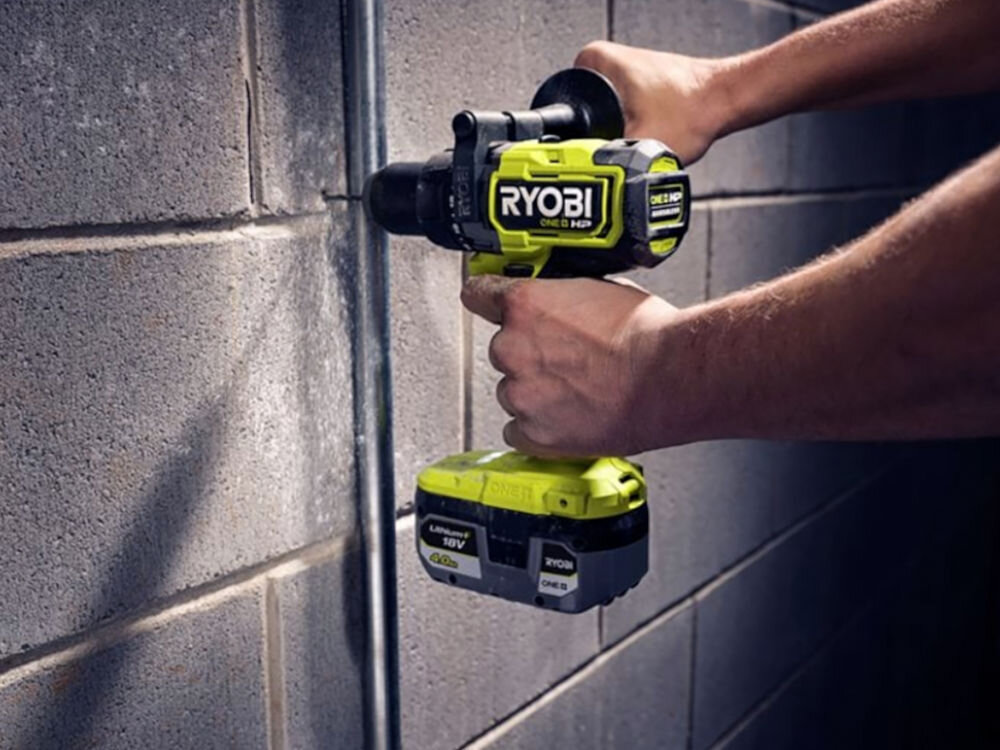 Akumulator RYOBI RB1840X 4Ah 18V, obudowa, odporność, IntelliCell, chłodzenie, Osoba wierci wiertarką w ścianie z wpiętym do niej akumulatorem